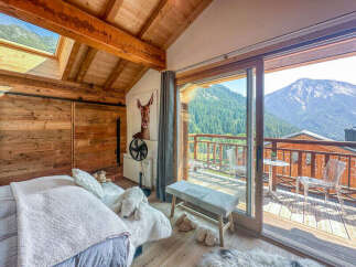 Experience breathtaking mountain views from this charming alpine bedroom, featuring a cozy bed and direct access to a private balcony.