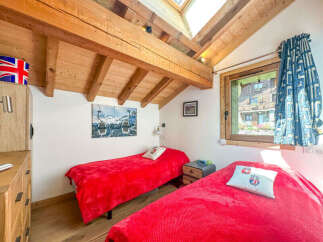 This charming bedroom features two cozy twin beds, each adorned with vibrant red blankets and decorative pillows.