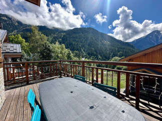 Enjoy breathtaking mountain views from this charming chalet's spacious wooden deck, complete with an outdoor dining table and seating.
