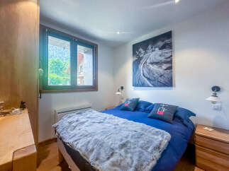 Experience cozy mountain living in this charming bedroom, featuring a plush blue duvet and a soft grey throw blanket perfect for chilly evenings.