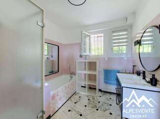 This charming bathroom features a classic pink tiled wall and a spacious bathtub, perfect for a relaxing soak.