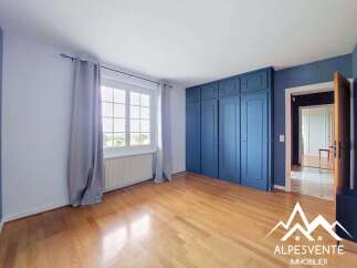Discover this spacious bedroom featuring a large window that floods the room with natural light, complemented by elegant grey curtains.