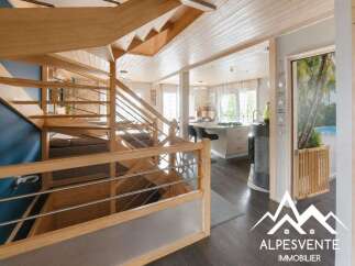 Discover this stunning modern home featuring a beautiful wooden staircase with sleek metal railings, leading to an open-plan living area.