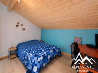 Discover this charming attic bedroom featuring a comfortable double bed with a vibrant blue and white polka dot comforter.