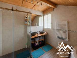 This charming bathroom features a spacious walk-in shower with a sliding glass door and a wooden vanity with two stone vessel sinks.