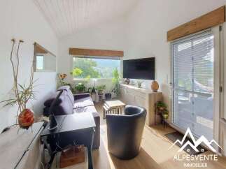 This bright and airy living room features a comfortable purple sofa, a modern entertainment center with a large flat-screen TV, and a stylish black armchair.
