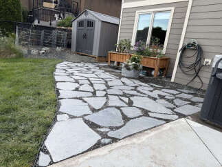 Enhance your outdoor living space with this charming backyard featuring a natural stone pathway leading to a cozy patio area.