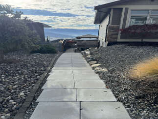 Discover this stunning property featuring a modern pathway leading through a meticulously landscaped yard with a mix of river rocks and dark gravel.