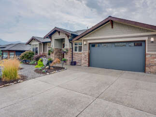 Discover this stunning home featuring a modern grey garage door and a charming stone facade.