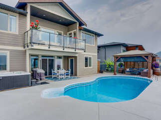 Experience luxury outdoor living with this stunning backyard featuring a sparkling swimming pool and a relaxing hot tub.