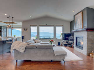 Experience breathtaking mountain and valley views from this stunning living room, featuring a cozy fireplace and a spacious sectional sofa perfect for relaxation.