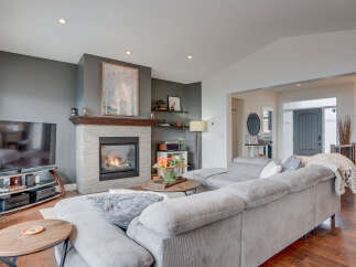 Experience modern living in this beautifully appointed living room, featuring a sleek gas fireplace with a stone surround and a stylish wood mantel.