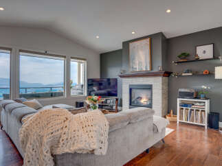 Experience breathtaking panoramic views from this stunning living room, featuring a cozy fireplace and a plush sectional sofa perfect for relaxation.