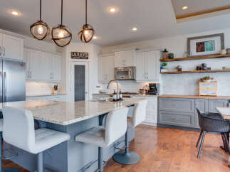 Experience modern living in this stunning kitchen, featuring a spacious island with granite countertops and comfortable bar seating.