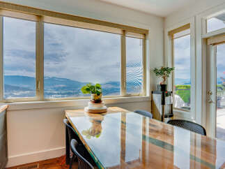 Enjoy breathtaking panoramic views from this stunning dining area, featuring a sleek glass-top table perfect for intimate meals.