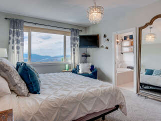 Experience breathtaking panoramic views from this stunning bedroom, featuring a plush white duvet and elegant blue accent pillows.