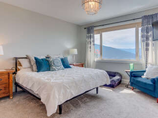 Experience breathtaking mountain and water views from this stunning bedroom.