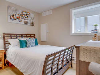 This inviting bedroom features a comfortable queen-size bed with crisp white linens and decorative teal and patterned throw pillows.
