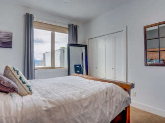 This bedroom features a comfortable bed with plush pillows and a textured duvet, complemented by elegant grey curtains framing a large window.