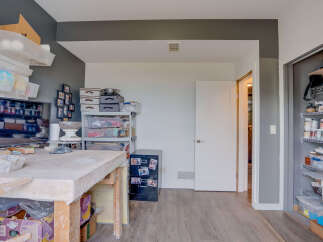 Discover a dedicated studio space perfect for creative endeavors, featuring ample storage solutions including wall-mounted bins and shelving units.