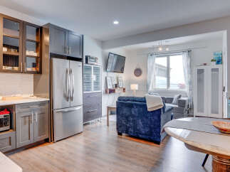 Discover modern living in this open-concept space, featuring a sleek kitchen with stainless steel appliances and ample cabinet storage.