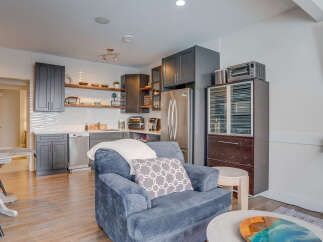 Discover this charming studio apartment featuring a modern kitchen with sleek dark cabinetry and stainless steel appliances, including a dishwasher and refrigerator.