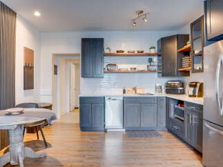 This modern kitchen features sleek dark gray cabinetry, complemented by warm wooden open shelving displaying decorative bowls and plants.