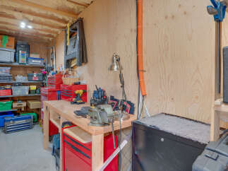 This workshop space is perfectly organized for any DIY enthusiast, featuring a sturdy workbench equipped with a vise and a variety of tools.