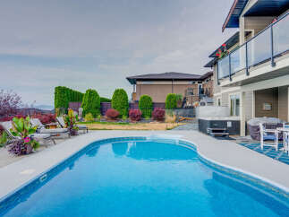 Experience luxury outdoor living with this stunning backyard featuring a sparkling swimming pool and a relaxing hot tub.