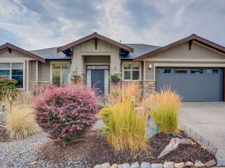 Discover this charming home featuring a welcoming covered entryway with decorative hanging baskets and a stylish dark gray front door.