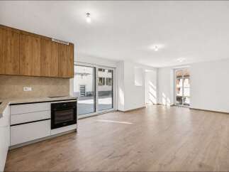 Discover modern living in this bright and airy open-concept space, featuring a sleek kitchen with wood-grain cabinetry and integrated appliances.