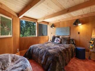 Experience rustic charm in this cozy bedroom, featuring a luxurious faux fur bedspread and warm wood-paneled walls.