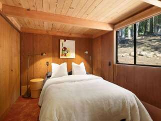 Experience rustic charm in this cozy bedroom featuring warm wood paneling and a plush white comforter.