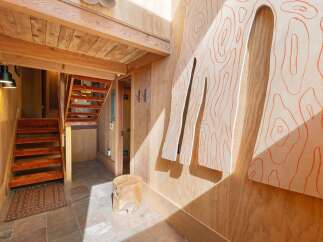 Discover this unique entryway featuring warm wood paneling and a striking abstract art piece with orange contour lines.