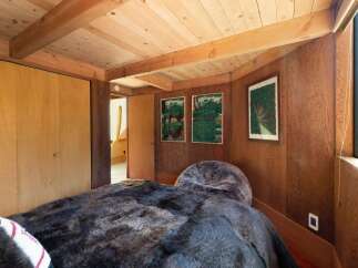 Experience rustic charm in this cozy bedroom featuring warm wood paneling and exposed beams.