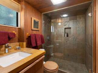 Experience rustic charm in this bathroom featuring a warm wood-paneled interior and a spacious walk-in shower with natural stone tile.