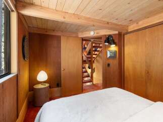 Step into a cozy bedroom featuring warm wood paneling and a slatted wood ceiling.