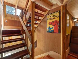 Ascend this charming wooden staircase, featuring plush brown carpeted treads, leading to the upper levels of this unique home.