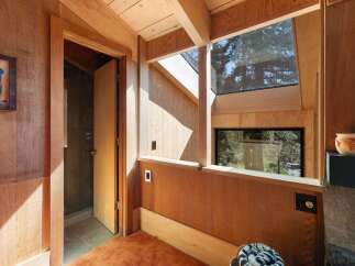 Experience rustic charm in this wood-paneled interior, featuring a unique open doorway leading to a tiled shower.