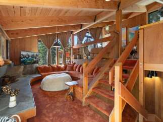 Experience rustic charm in this unique living space featuring a curved, plush orange sectional sofa and a large, cozy white beanbag chair.