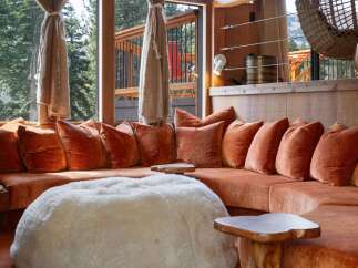 Experience ultimate relaxation in this cozy living space, featuring a plush, rust-colored sectional sofa adorned with velvet pillows.