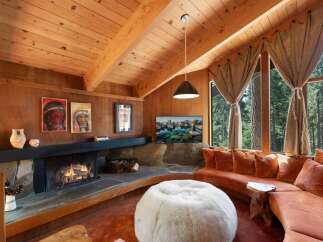 Experience rustic charm in this cozy living room, featuring a stone fireplace and a large, curved sectional sofa perfect for gathering.