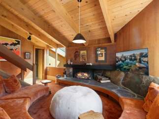 Experience rustic charm in this living room featuring a stunning stone fireplace and a cozy, curved sectional sofa.