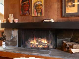 Cozy up by the fireplace in this inviting living space, featuring a rustic stone hearth and a warm, wood-paneled accent wall.