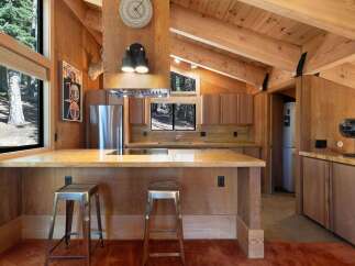 Experience rustic charm in this mountain kitchen featuring warm wood paneling and exposed beams.