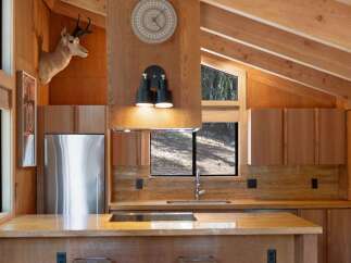 Experience rustic charm in this beautifully appointed kitchen, featuring warm wood cabinetry and a stunning stone backsplash.