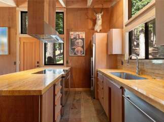 Experience rustic luxury in this stunning kitchen, featuring warm wood paneling and a striking mounted antelope head.