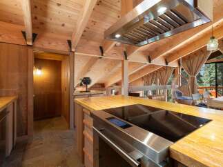 Experience rustic charm in this mountain kitchen featuring a sleek induction cooktop and a striking granite countertop.