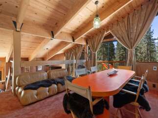 Experience rustic charm in this mountain retreat featuring a spacious living area with a plush leather sofa adorned with faux fur throws.