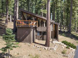 Nestled amidst towering pine trees, this charming A-frame cabin offers a serene mountain retreat.